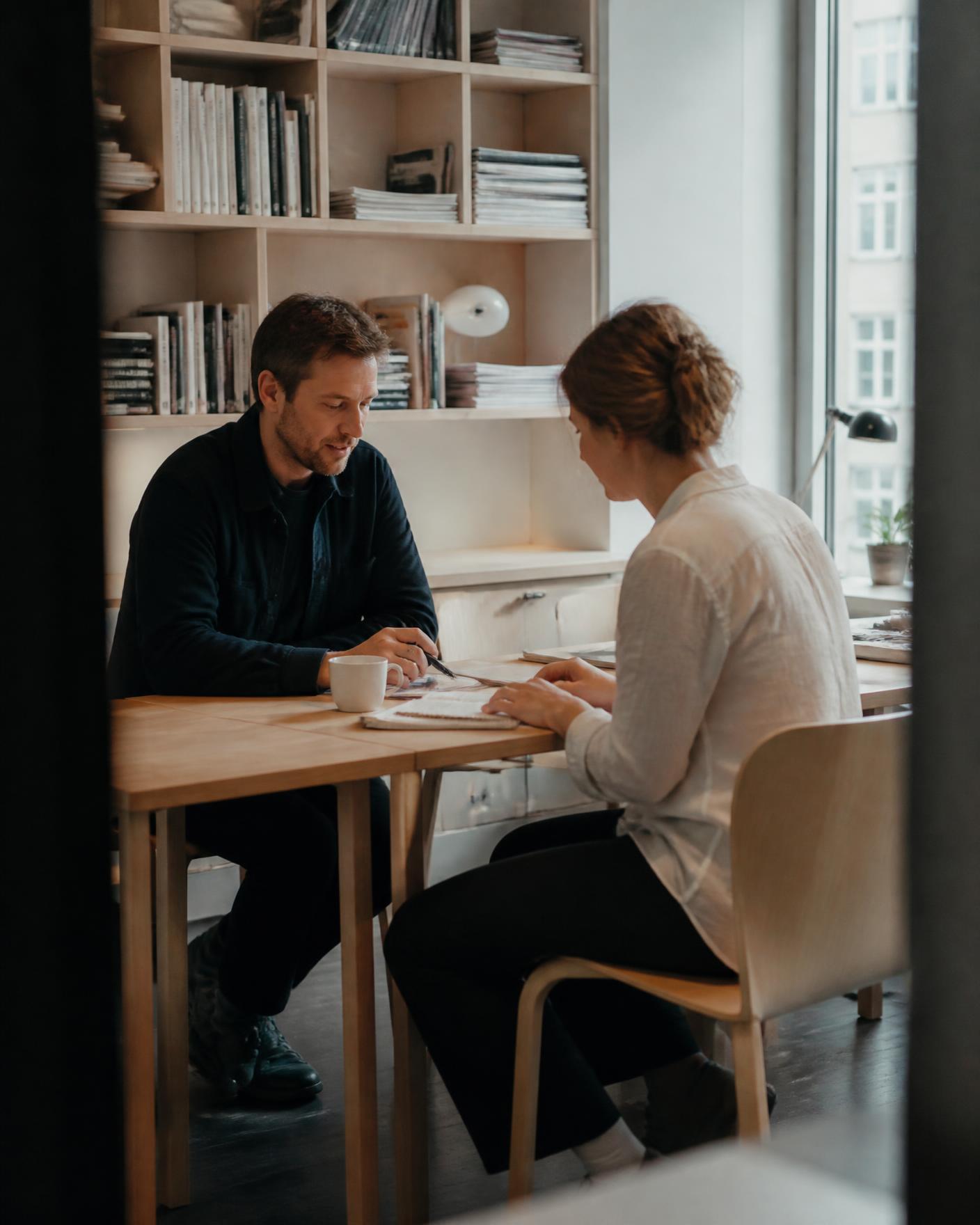 Två kollegor i samtal vid ett bord i ett ljust kontorsrum
